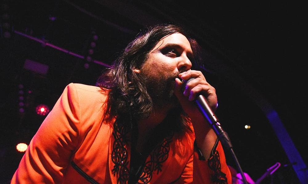 Honus Honus singing onstage in an orange blazer.